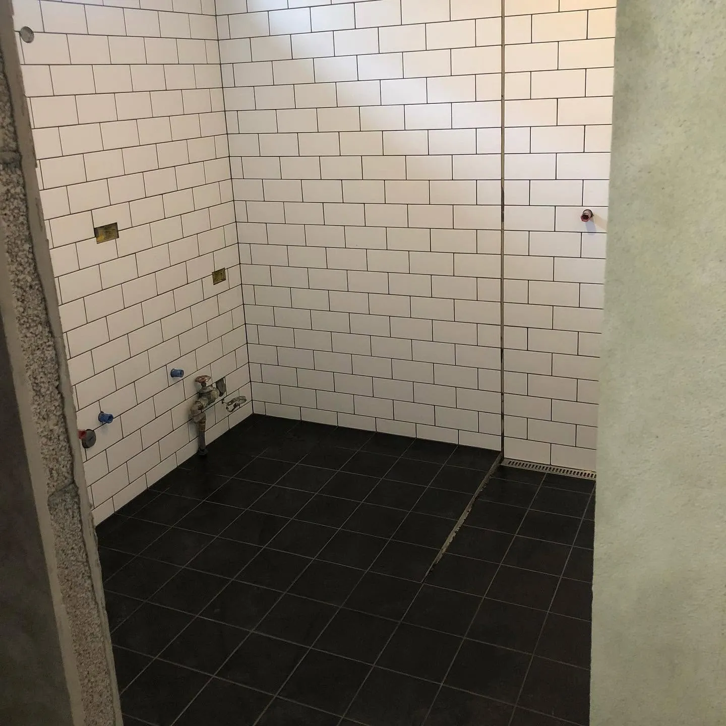 Hvítar subway-flísar og svartar gólfflísar í sturtu